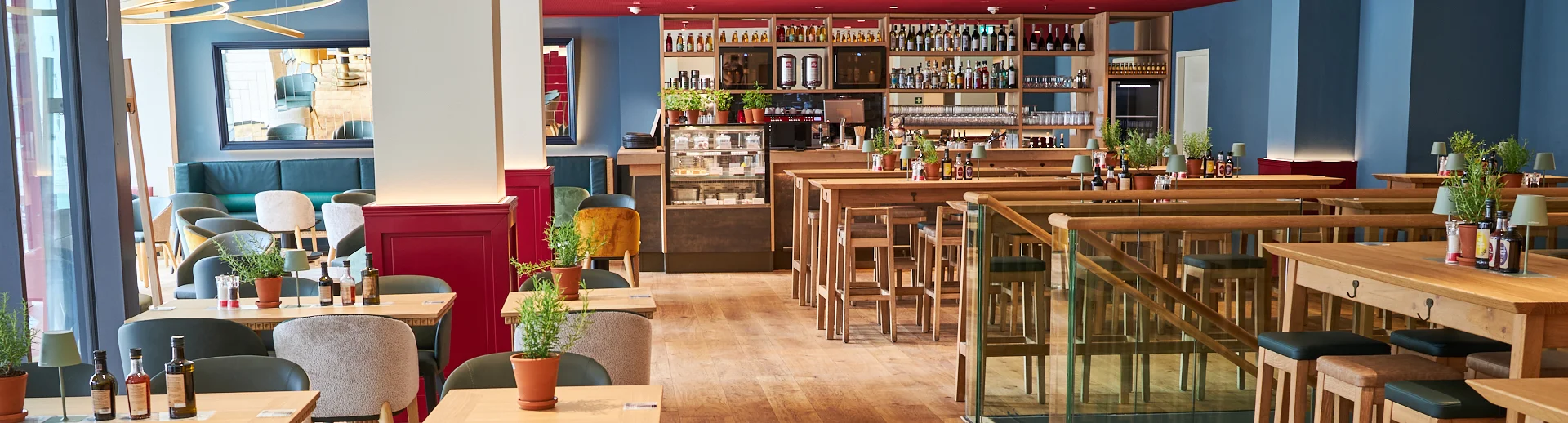 Innenaufnahme vom VAPIANO Hamburg Gänsemarkt mit Tischen, Stühlen und der Bar im Hintergrund.