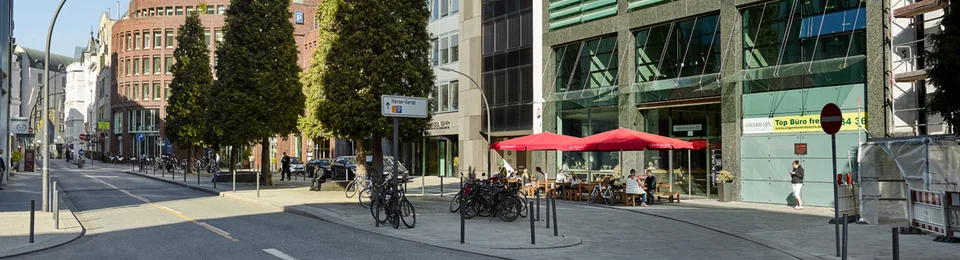 Außenansicht vom VAPIANO Hamburg Kurze Mühren mit Bänken und roten Sonnenschirmen.