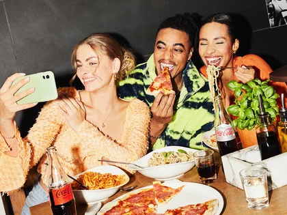Drei Gäste machen ein Foto mit dem Handy im Restaurant. 