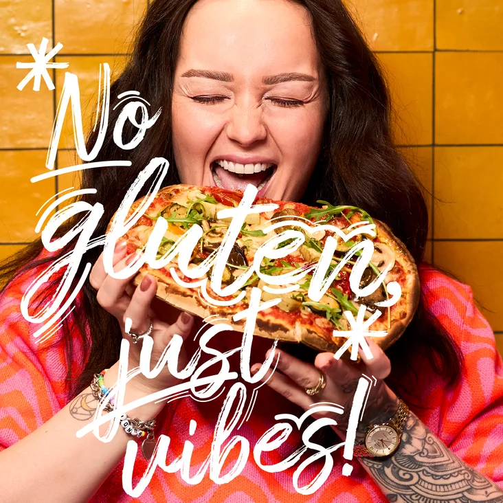 Eine Frau hält eine Pinsa und freut sich.