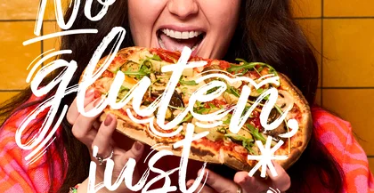 Eine Frau hält eine Pinsa und freut sich.