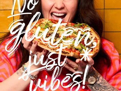 Eine Frau hält eine Pinsa und freut sich. 