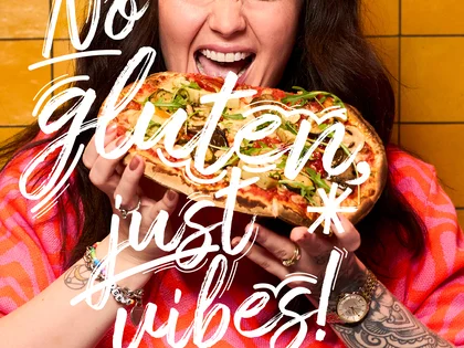 Eine Frau hält eine Pinsa und freut sich.