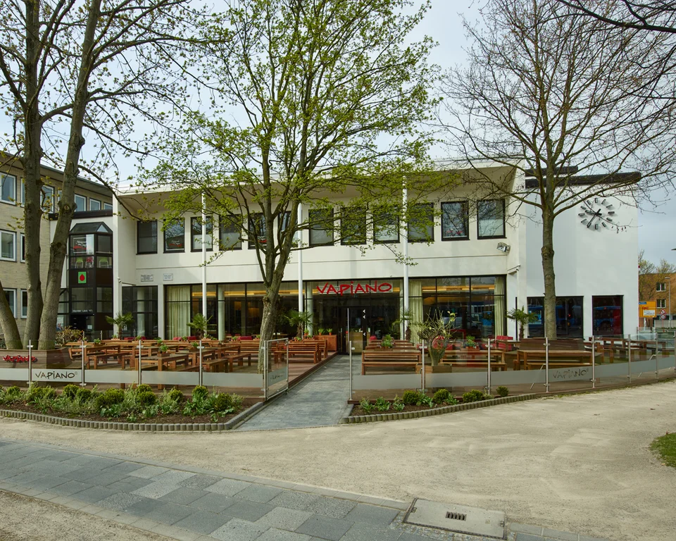 Außenansicht vom VAPIANO Göttingen mit einem großen Außenbereich mit Bänken und Pflanzen.