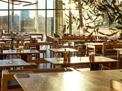 Innenaufnahme vom VAPIANO Berlin Europaplatz mit Tischen und Stühlen vor großen Fenstern. 