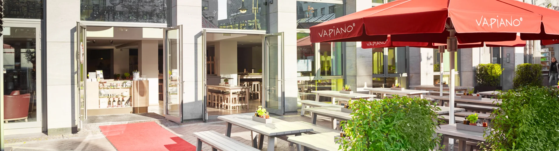 Außenansicht vom VAPIANO Bochum mit Bänken und Tischen im Außenbereich.