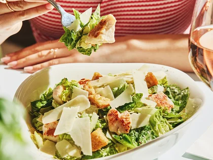 Ein Gast isst einen Salat mit Besteck.