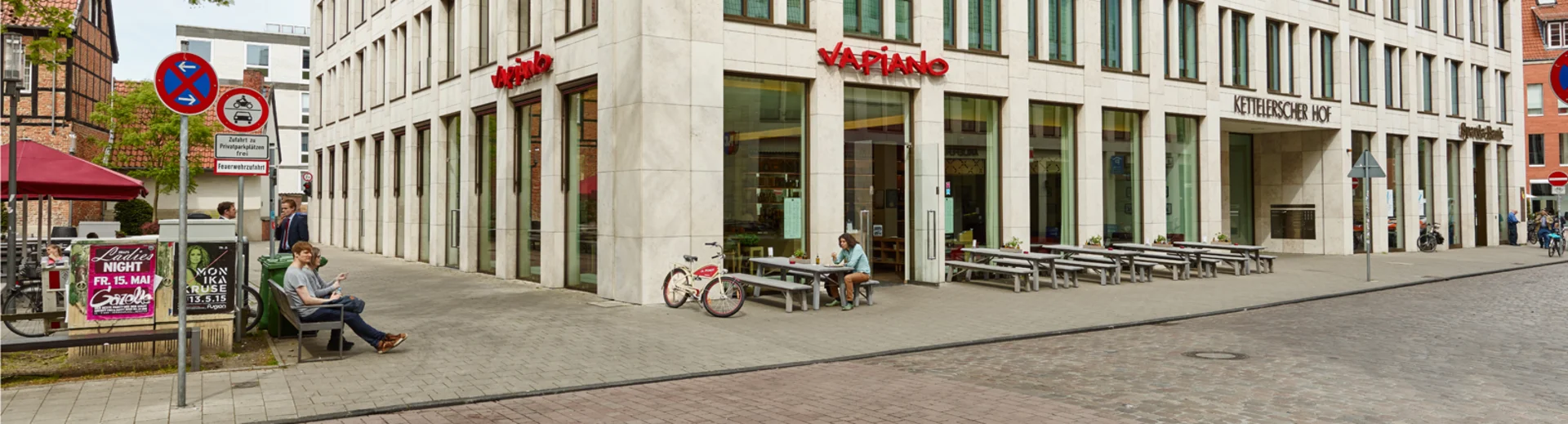 Außenansicht vom VAPIANO Münster mit Bänken und Tischen im Außenbereich.