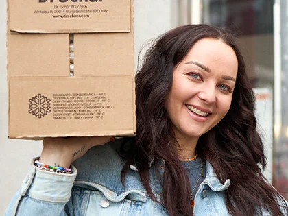 Eine Frau trägt einen Karton von "Dr. Schär"