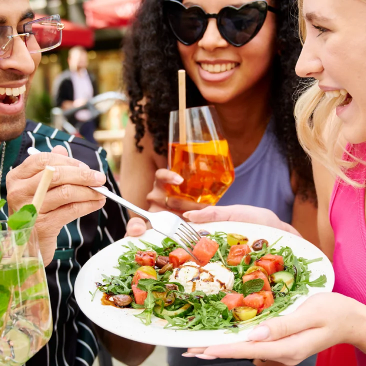 Links eine Bruschetta und rechts ein Insalata mit Feta und Melone. In der Mitte steht "More Drinks. More Fun! Summer Bundles"