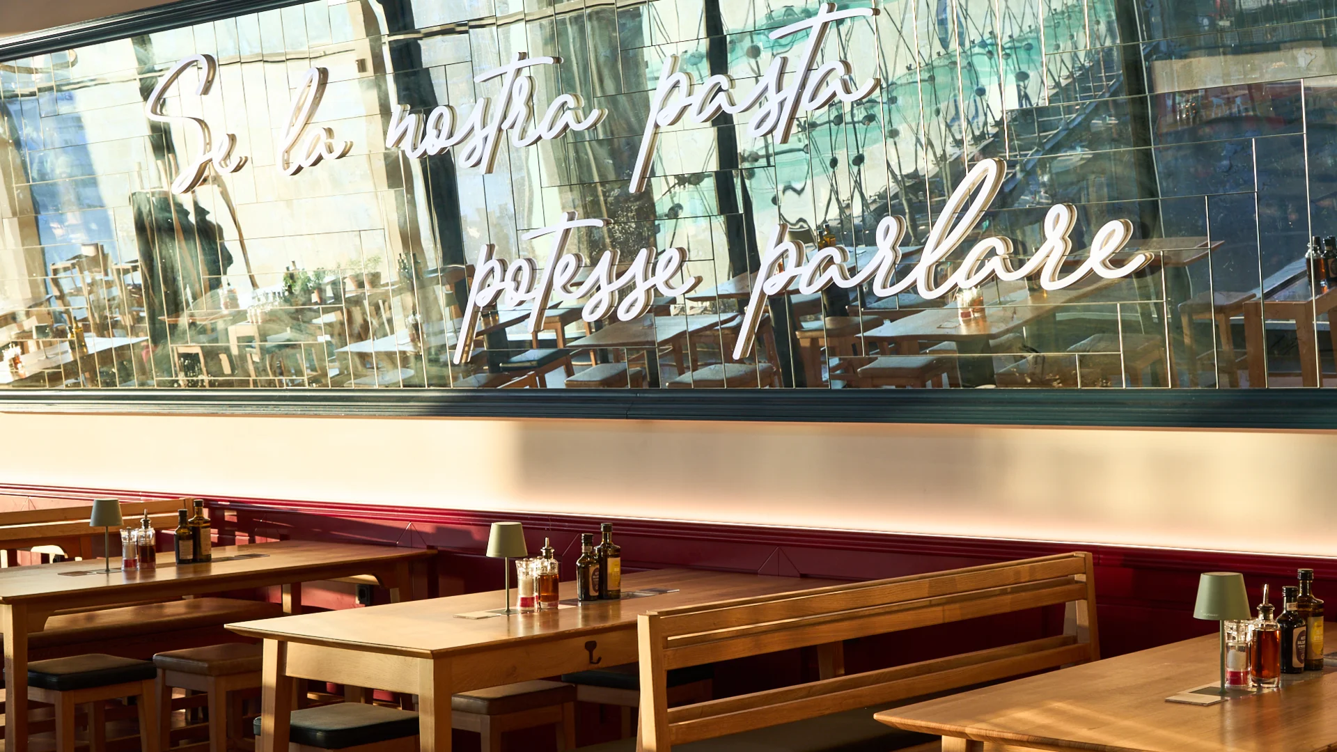 Sitzplätze im VAPIANO Berlin Europaplatz mit einem großen Spiegel an der Wand.