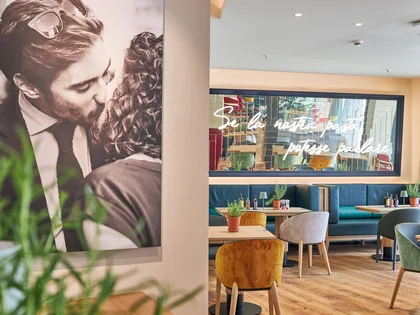 Innenaufnahme vom VAPIANO Hamburg Gänsemarkt mit einem dekorativen Foto an der Wand und einem Spiegel über den Sitzmöglichkeiten im Hintergrund.