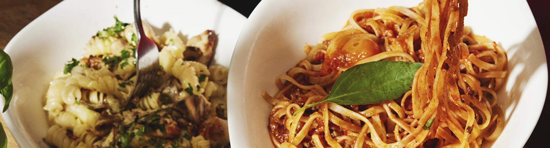 Personen essen verschiedene Pasta-Gerichte am gedeckten Tisch.